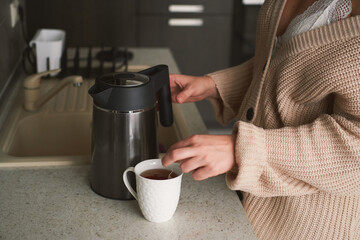 Portrait of young beautiful woman drinking coffee at home in kitchen