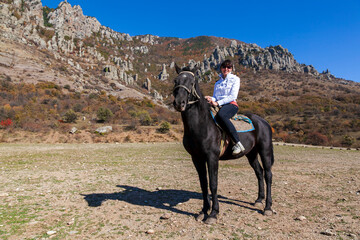 Pretty girl riding horse on the background of a mountain range