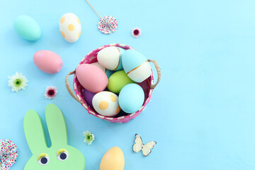 Fototapeta na wymiar Cute bunny next to easter colorful eggs over pastel background
