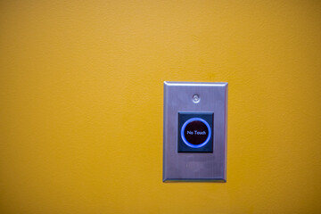 No touch opening button against yellow painted wall
