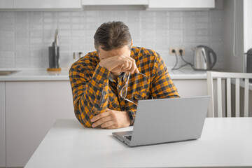 A middle-aged man during an online meeting with a psychologist. He covered his face with his hand.