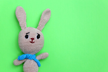 Easter Bunny on light green background. Greeting card with knitted toy rabbit with free copy space