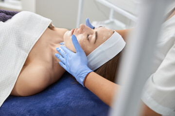 Professional cosmetologist is doing procedures for client in light cabinet