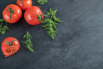 Three fresh tomatoes with leaves on a dark background