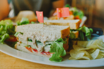 A club sandwich on a rustic table in bright lighte 