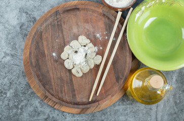 Raw dumplings with flour on a wooden board