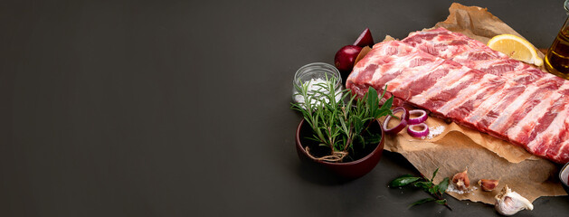 Fresh raw pork ribs seasoned with spices on dark background.