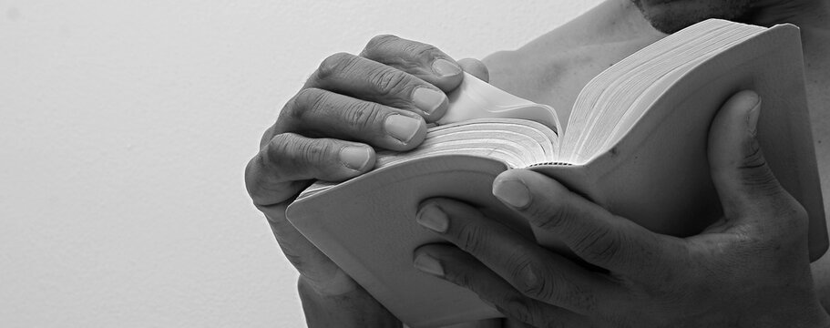 man praying with hand on the bible stock photo