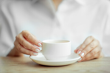 a girl in a white blouse holds a white mug in her hands