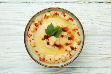 Bowl of hummus on white wooden background