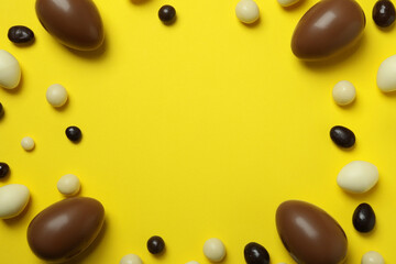 Easter chocolate eggs and candies on yellow background