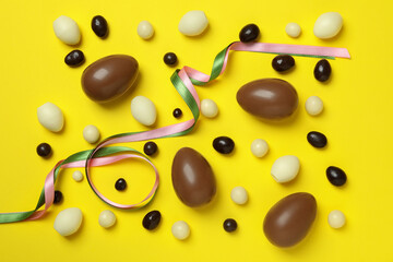 Easter chocolate eggs and candies on yellow background
