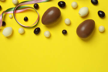 Easter chocolate eggs and candies on yellow background