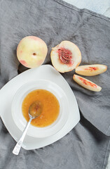 A white plate with peach jam and slices of brown bread