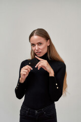 Beautiful young woman wearing black clothes looking at camera, holding plastic credit card while posing isolated over gray background