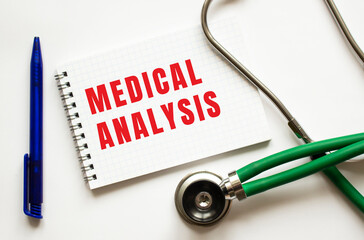 MEDICAL ANALYSIS is written in a notebook on a white table next to pen and a stethoscope.
