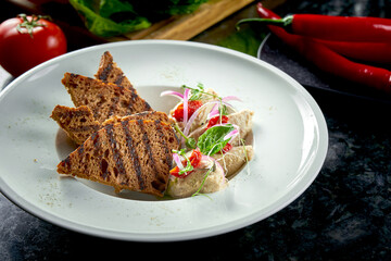 Classic dish of Israeli cuisine - herring forshmak with croutons served in a white plate on a marble background. Seafood.