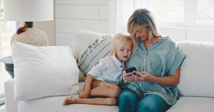 Mother and son using phone together on the couch at home, quality time together, modern technology, family lifestyle
