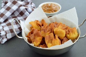 Deep fried beef wontons in a wok served with peanut sauce 
