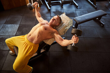 Obraz premium Optimistic sportsman looking energised during dumbbells workout