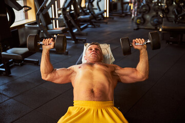 Naklejka premium Committed muscular man doing exercises with dumbbells