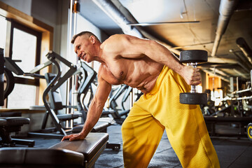 Mature bodybuilder exercising with set of dumbbells