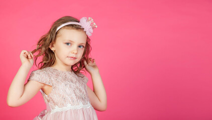 Obraz na płótnie Canvas Portrait 5-6 year old girl in dress on pink isolated background looks at camera. Concept Playing and Children Recreation. Little child in casual clothes posing and showing emotions. Copy space