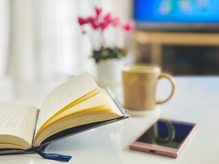 開いた本とスマホとコーヒーカップとテレビイメージ