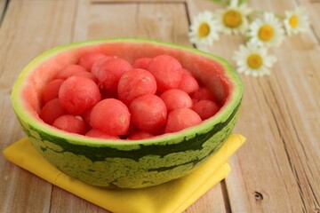 Fruit salad of watermelon balls in a watermelon skin bowl, daisy flower at the background