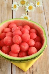 Fruit salad of watermelon balls in a watermelon skin bowl, daisy flower at the background