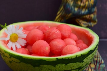 Watermelon balls in a watermelon skin bowl, garnish with daisy flower 