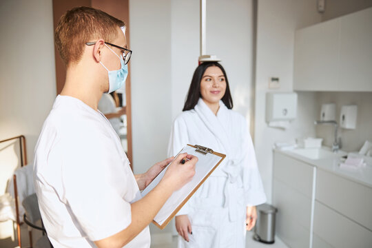 Pleased Patient Having Her Height Measured At The Doctor Office