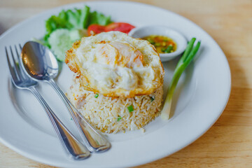 Fried rice with eggs on the white dish on wooden table 