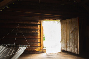 A hammock and a door to fresh air in a traditional log Russian village house.