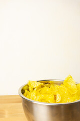 Stainless steel bowl full of potato chips on a wooden table