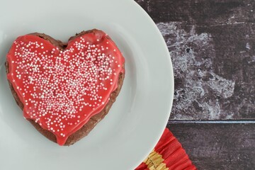 Obraz na płótnie Canvas Heart shaped Valentine's cookie with red sugar glaze and sprinkles. Flat lay