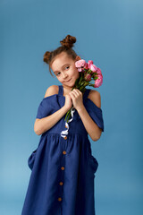 shy happy little girl holding bouquet of pink roses on blue background.