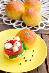 Sesame burger with tomato, mozzarella and basil leaves