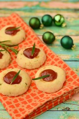 Homemade rosemary thumbprint cookies with jam on green wooden background. Decorated with Christmas green balls
