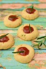 Homemade rosemary thumbprint cookies with jam on green wooden background. 