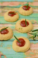 Homemade rosemary thumbprint cookies with jam on green wooden background. 