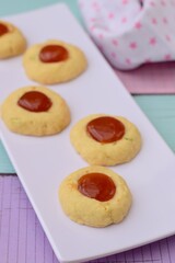 Homemade thumbprint cookies with jam on white serving plate. pastel color background
