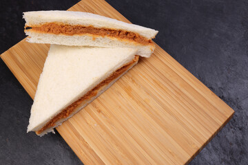 Tuna fish spread sandwich white bread on wooden board over black slate background