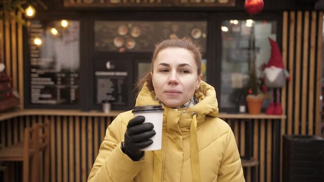 Portrait of young woman drinking take away coffee. Beautiful adult girl standing on urban street with paper cup of hot drink.4k