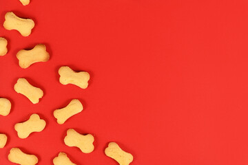 Bone shaped dog biscuits in corner of red background wih empty copy space