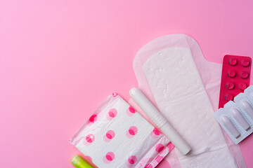 Obraz na płótnie Canvas Сontraceptive pills, hygienic pads and tampons on pink background