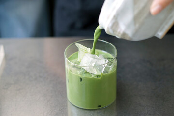 Iced matcha latte - A glass of green tea with milk on the table, Summer refreshment drinks.