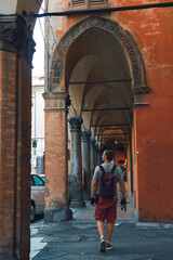 Fototapeta na wymiar Tourist man with backpack walk on the street in Italy. Summer day. Vertical photo. Bologna