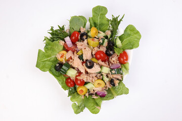 Tuna fish meat salad cucumber tomato onion black green olive leaf lettuce on white plate over white background