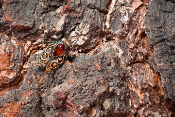 Ring in the form of a cicada of bronze and amber on the wooden bark of birch slice